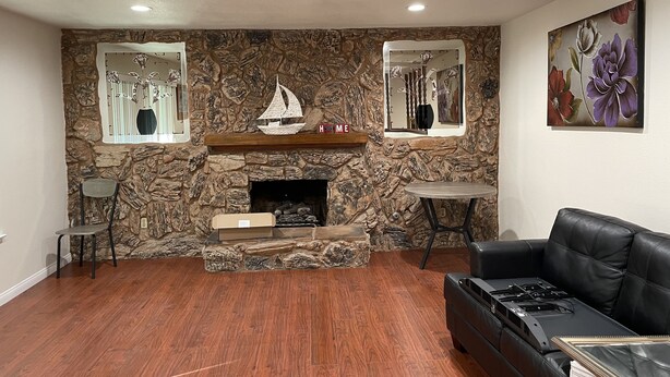 A living room with a stone wall, fireplace, and a painting of flowers. - Cheerful home,4bedrooms,6beds,2baths,TV,Central AC (Fontana)