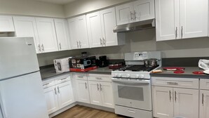 A modern kitchen with white cabinets, a stainless steel range hood, a built-in oven, and a microwave. - Cheerful home,4bedrooms,6beds,2baths,TV,Central AC (Fontana)