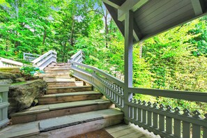 A wooden staircase with white railings leading up a hill, surrounded by lush greenery. - Inspiration Point by Taylor Made Deep Creek (Swanton)