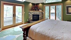 A bedroom with a large bed, a fireplace, and a view of the outdoors. - Inspiration Point by Taylor Made Deep Creek (Swanton)