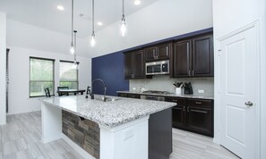 Enjoy cooking in this well-equipped kitchen with a large island, stainless steel appliances, and a sink with a modern faucet.