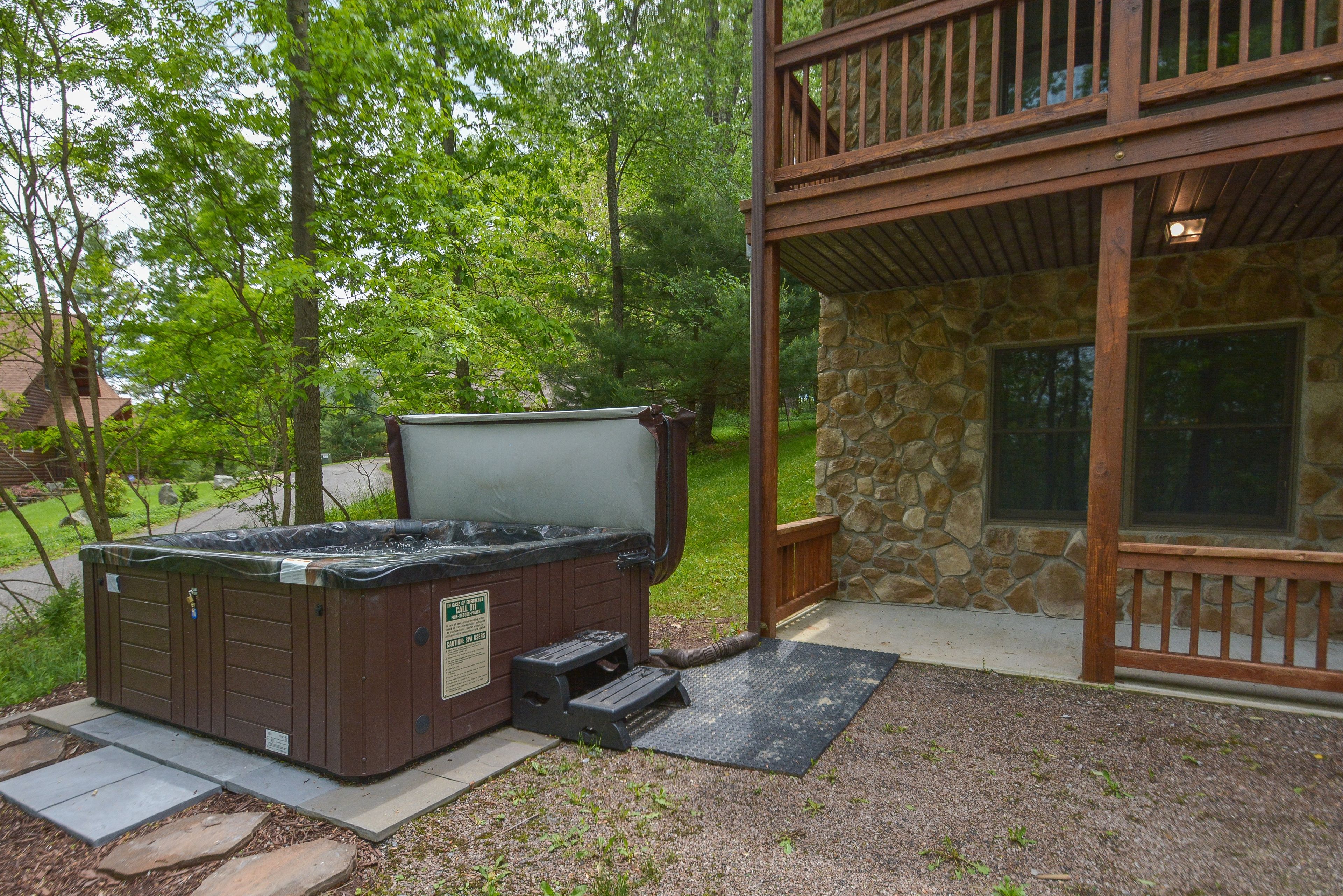 A hot tub in a backyard with a stone wall and wooden deck.