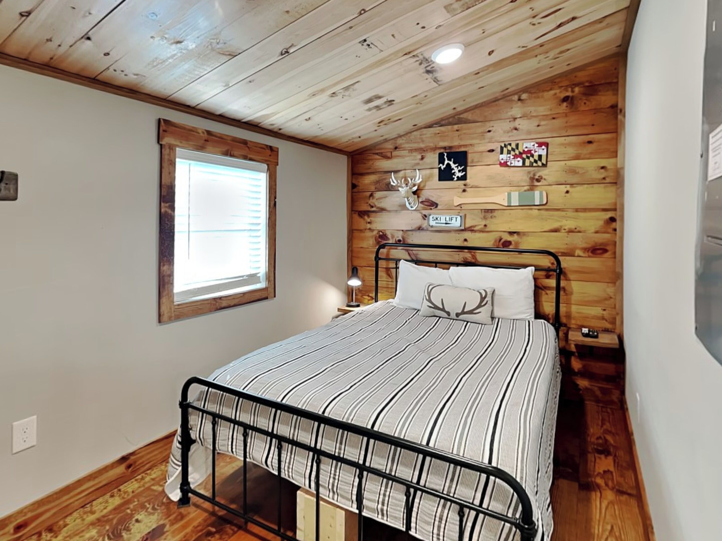 Un dormitorio con cama, paredes de madera, una ventana y un cartel de telesilla.