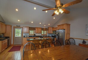 A spacious kitchen with wooden cabinets, a central island, and a ceiling fan. - Keep Calm and Lake On by Taylor Made Deep Creek (Swanton)