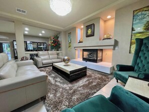 A modern living room with a fireplace, a sofa, a coffee table, and a green armchair.