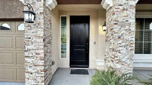 A house entrance with a black door, stone pillars, and a garage door. - Luxury, Cheerful & Spacious 5 Bedroom Home! Free P (Las Vegas)