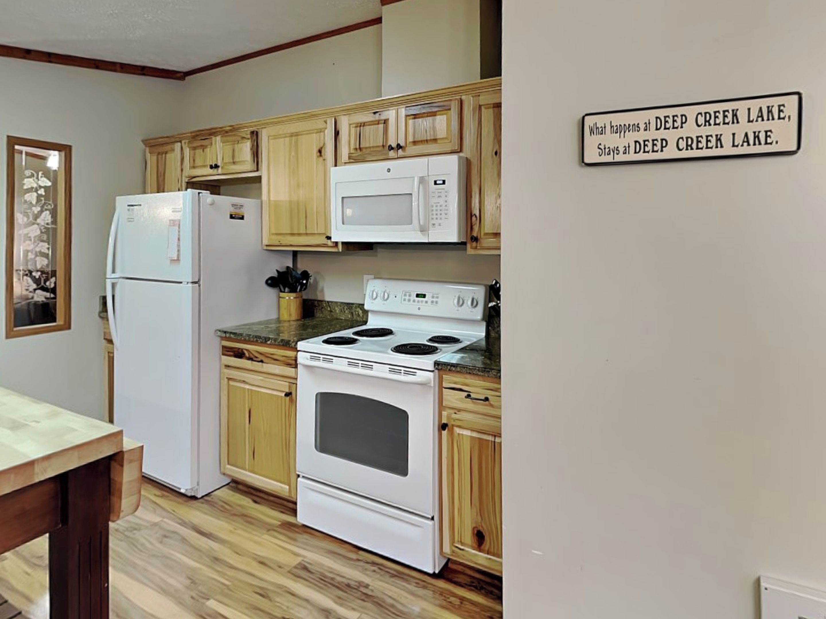 A kitchen with wooden cabinets, a refrigerator, a microwave, and a stove.