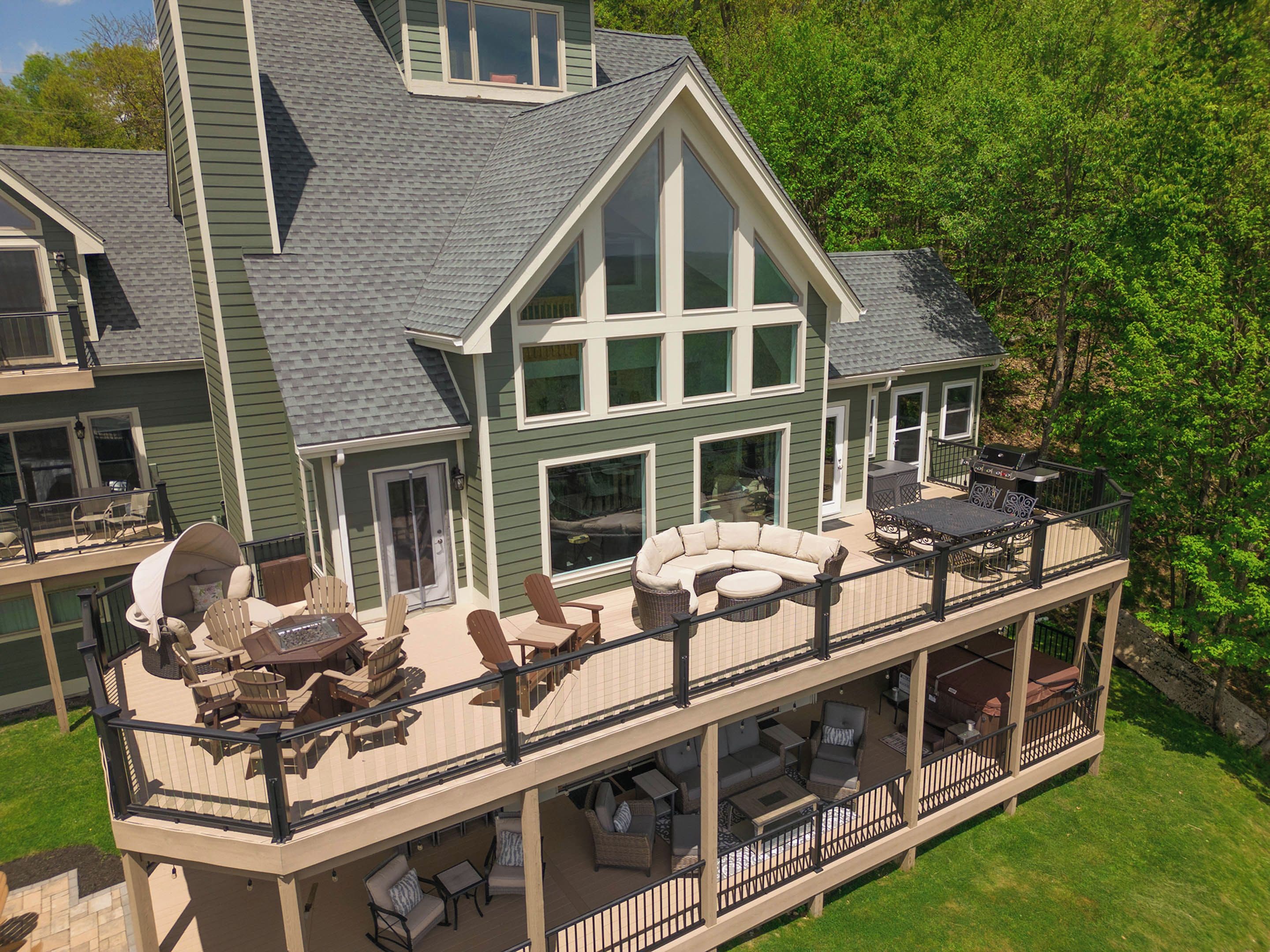 A large house with a covered deck area featuring outdoor furniture and a barbecue.