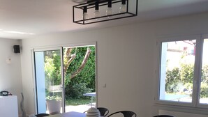Comedor con mesa de madera y seis sillas, lámpara colgante y vista a plantas al exterior.