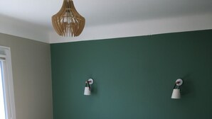 Un dormitorio con cama, mesitas de noche, una lámpara de pared y una ventana.