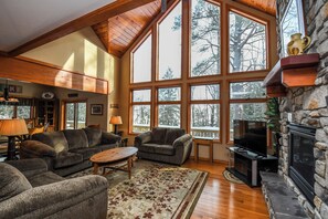 A spacious living room with large windows, a fireplace, and a cozy seating area. - Lake House by Taylor Made Deep Creek (Oakland)