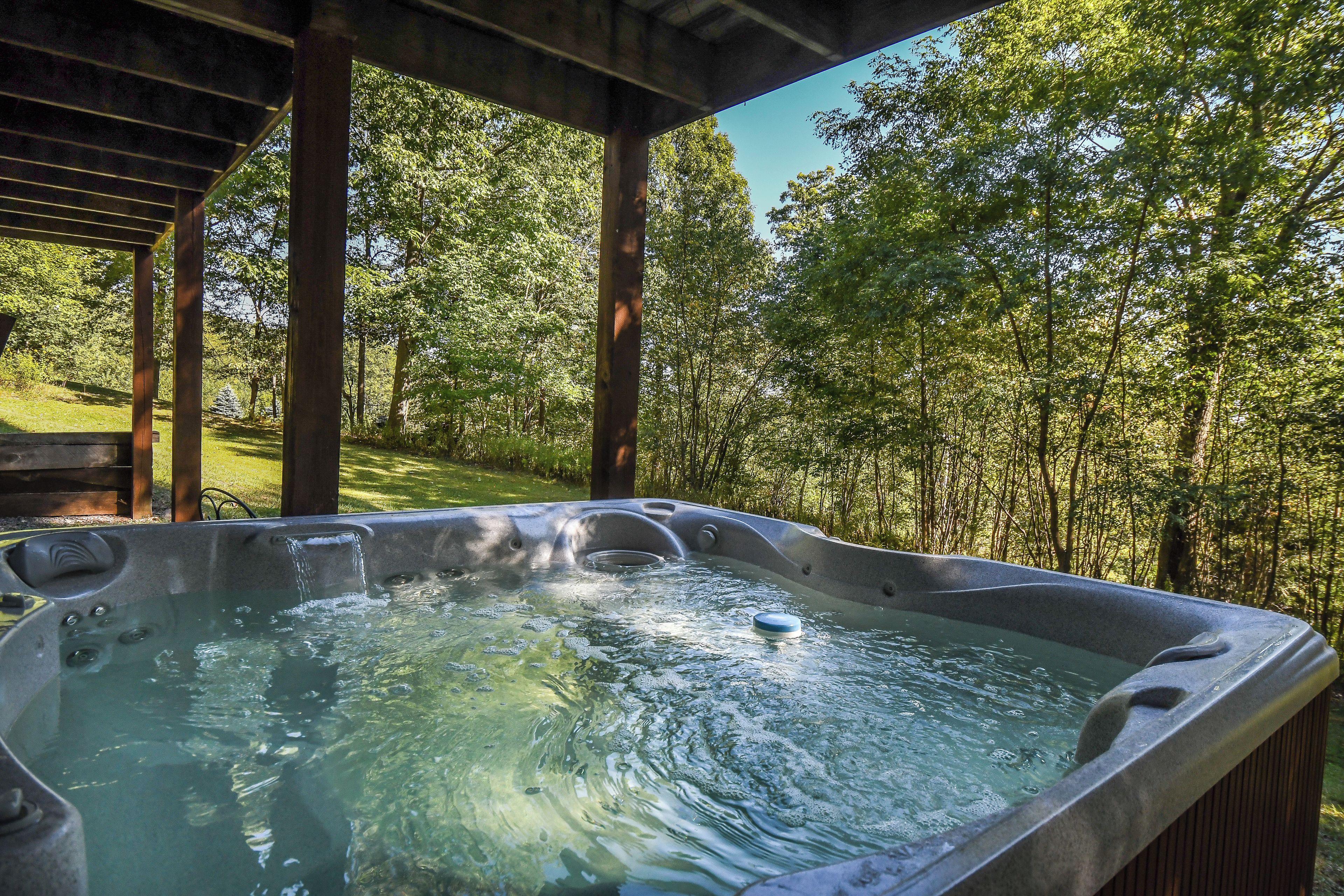 A hot tub in a covered outdoor area surrounded by trees.