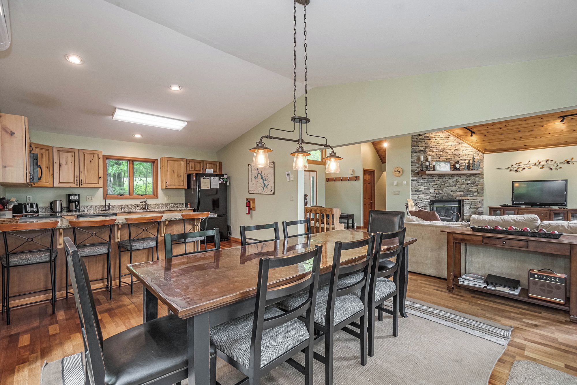 A spacious kitchen with wooden cabinets, a central island, and a dining area with chairs and a table.