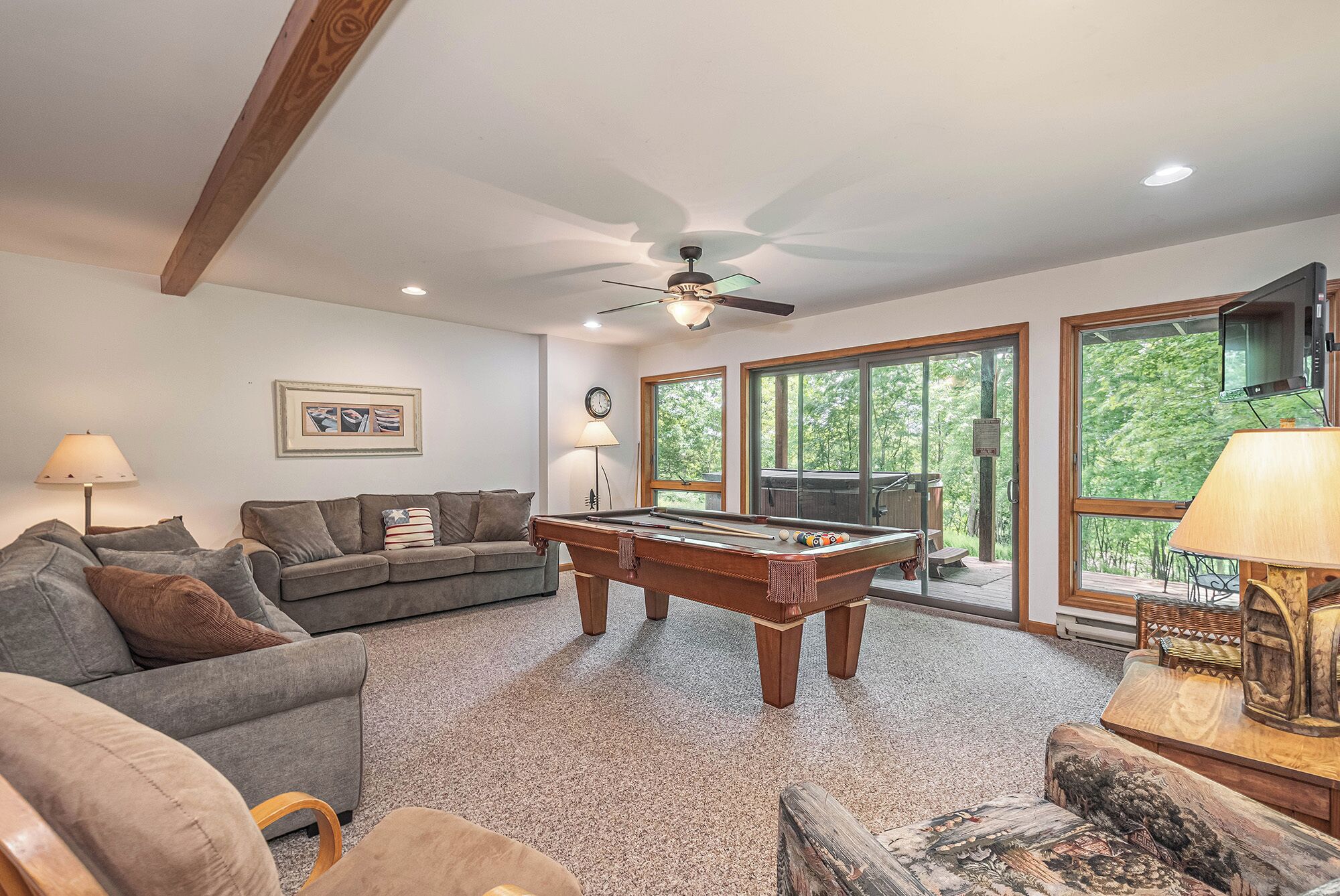 A living room with a pool table, a sofa, and a television.