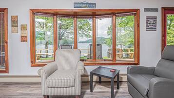 A room with a large bay window, a striped armchair, a grey sofa, and a small table.