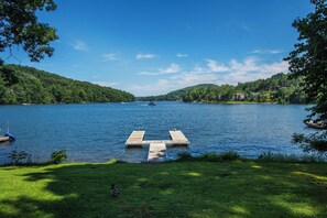 A lake with a wooden dock extending into the water, surrounded by lush greenery and hills in the background. - Lake View by Taylor Made Deep Creek (Oakland)