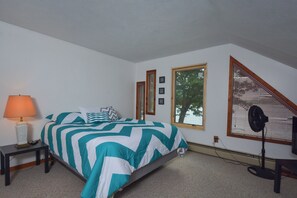 A bedroom with a bed, a nightstand, a lamp, a window with blinds, and a fan. - Lake View by Taylor Made Deep Creek (Oakland)
