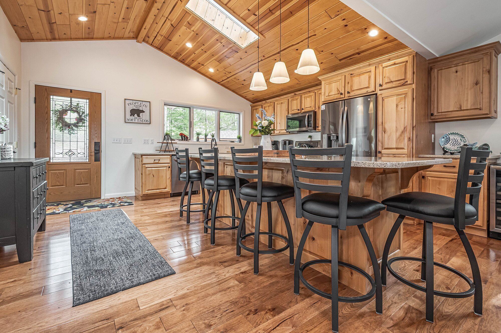 Una cocina amplia con armarios de madera, una isla central con taburetes de bar y un refrigerador grande.