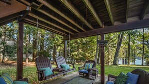 A covered outdoor seating area with wicker furniture, a glass table, and a sign indicating a campground. - Lakeside Dreamin' by Taylor Made Deep Creek (McHenry)