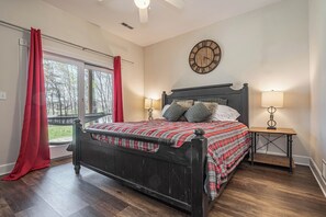 Ein Schlafzimmer mit einem hölzernen Bett, einer Wanduhr und einem Fenster mit roten Vorhängen.