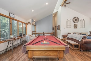 A pool table in a room with a large window, a wooden bench, and a couch. - Lakeside Vista by Taylor Made Deep Creek (Oakland)