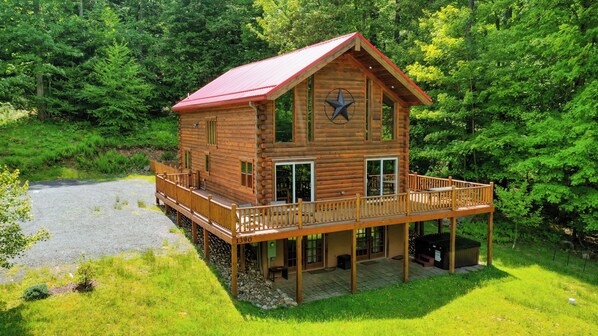 A log cabin with a balcony and a deck, surrounded by lush greenery. - Lakestar Chalet by Taylor Made Deep Creek (Oakland)