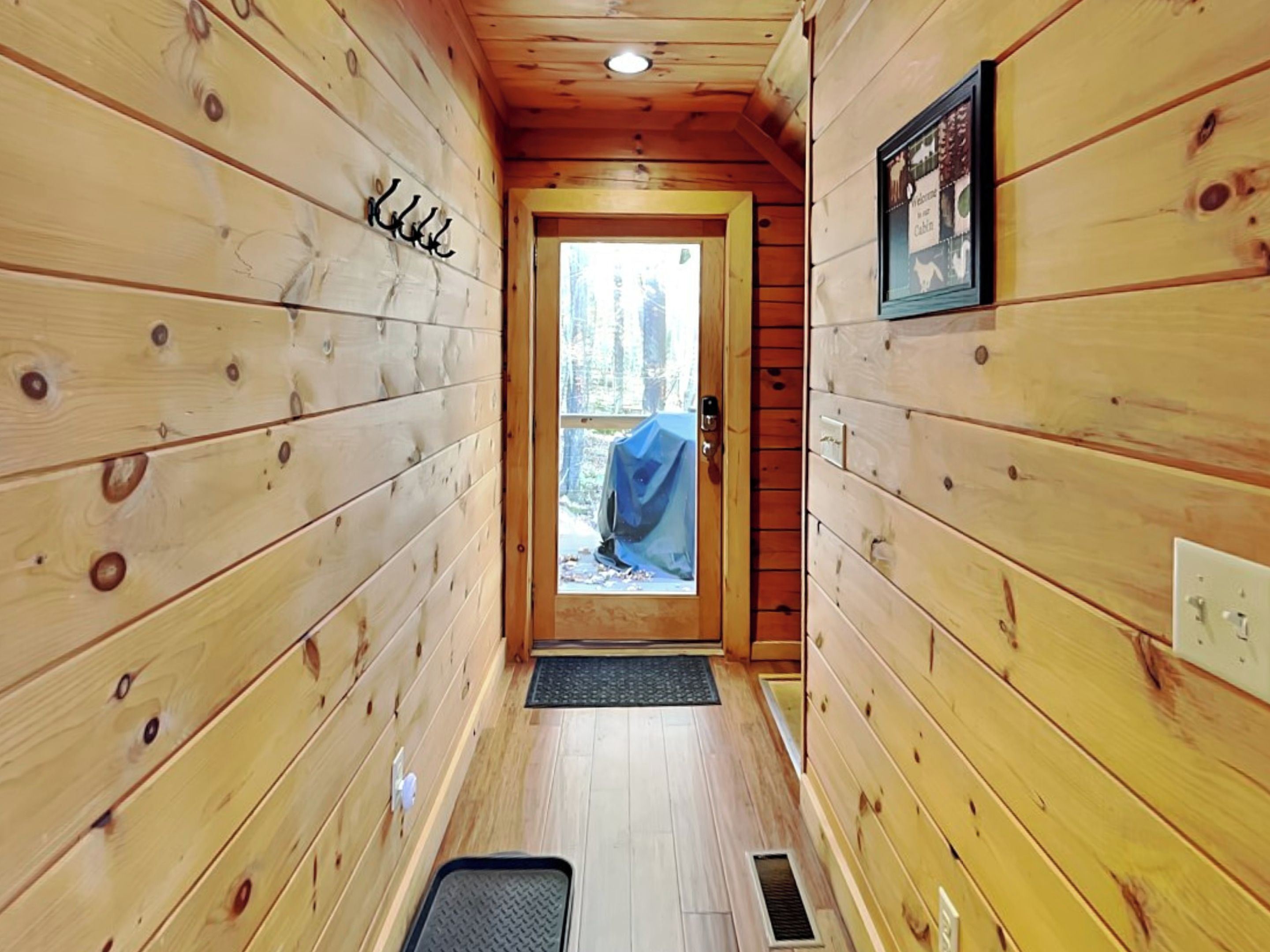 A narrow wooden hallway with a door leading to an outdoor area.