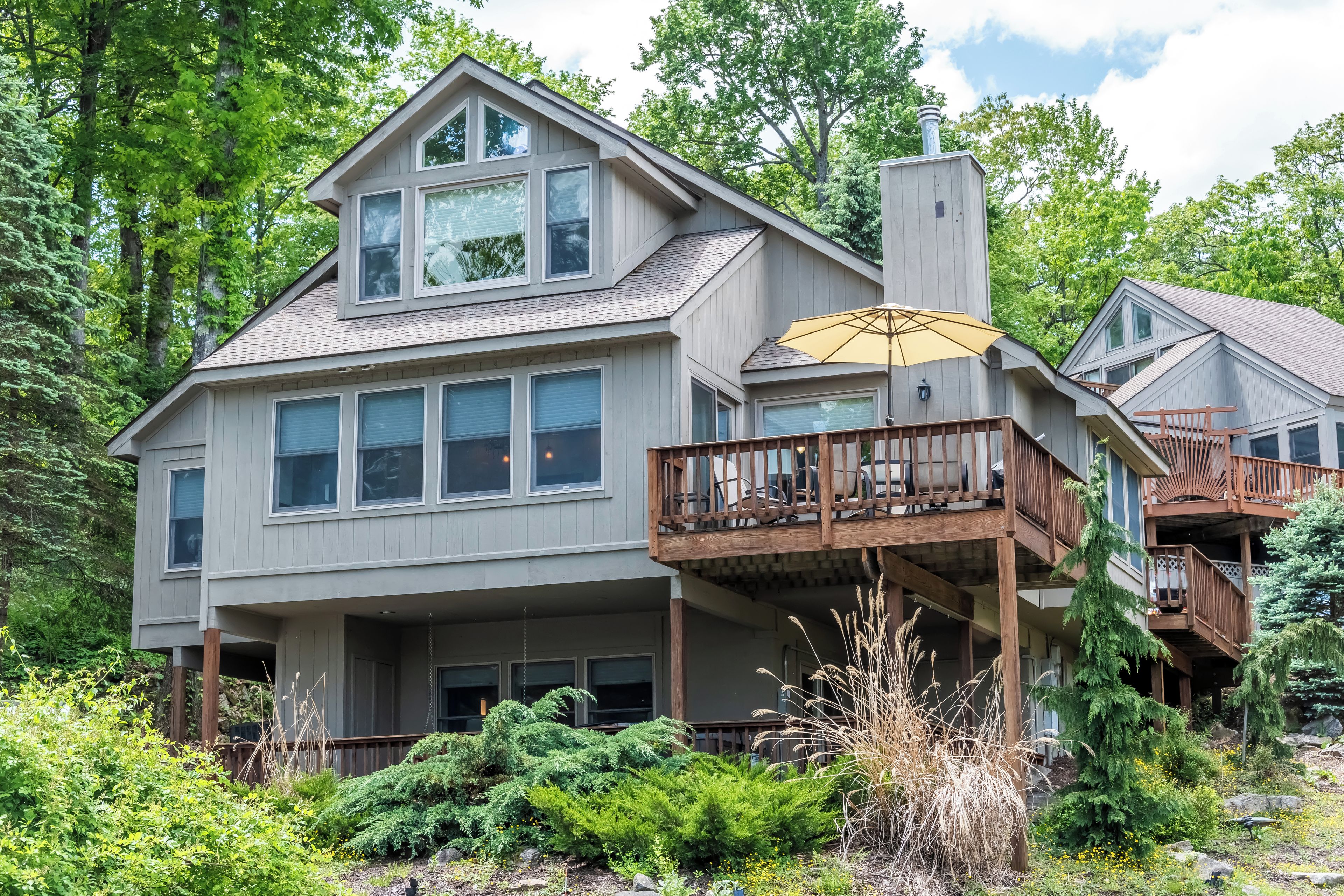 A two-story house with a balcony and a covered outdoor seating area.