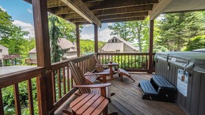 Una terraza de madera con sillas Adirondack y un jacuzzi.