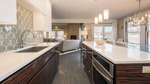 Una cocina moderna con una isla central, electrodomésticos integrados e iluminación colgante.