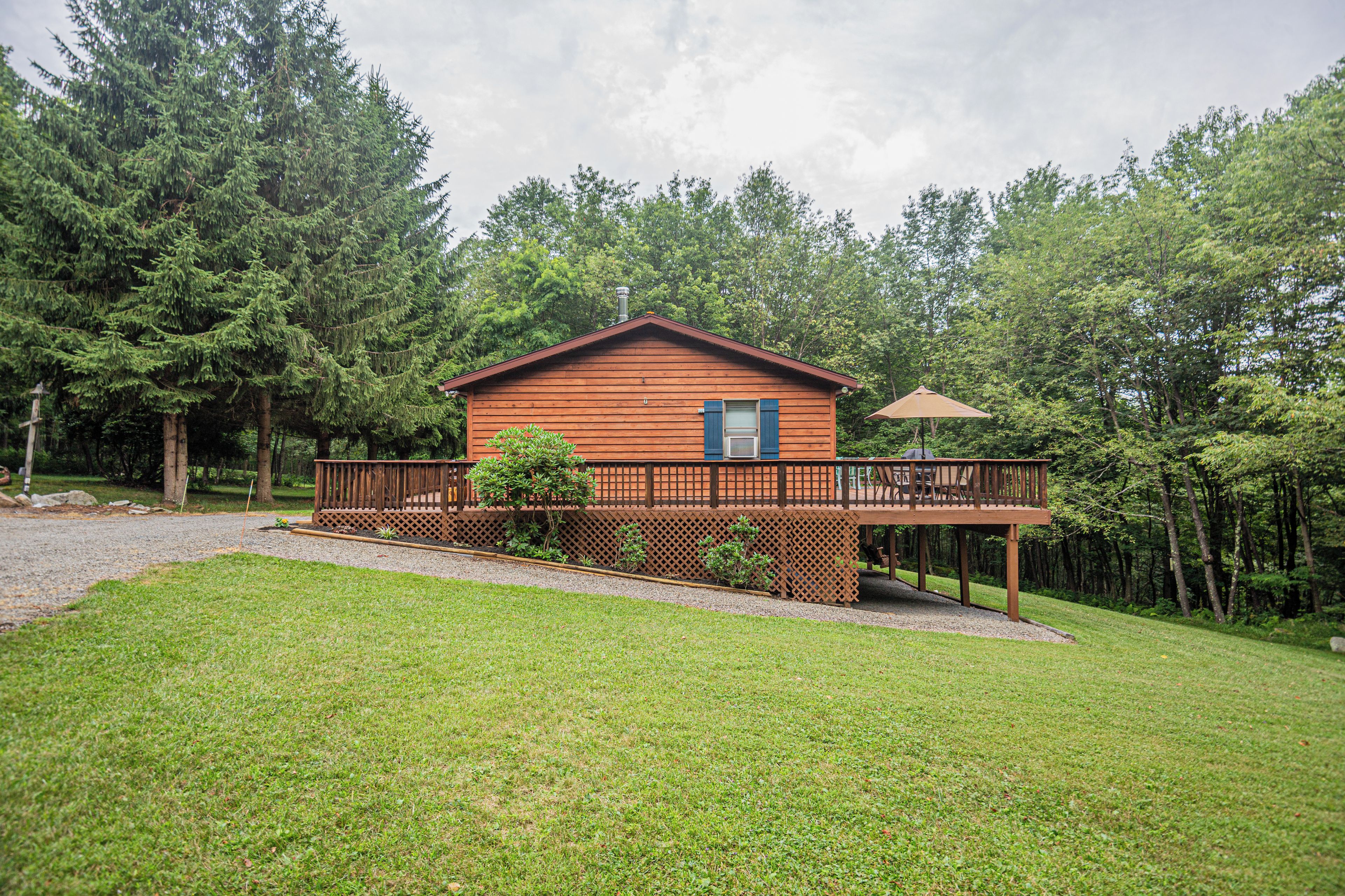 A wooden cabin with a deck, surrounded by trees.