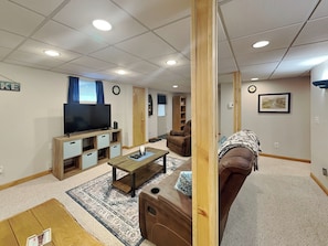 Un salon moderne doté d’un téléviseur à écran plat, d’un meuble de rangement en bois, d’un canapé en cuir marron et d’un tapis à motifs.