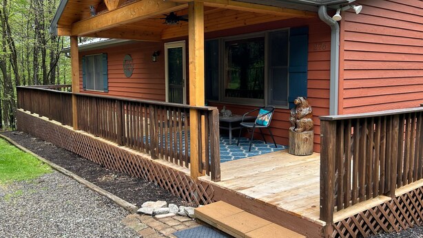A wooden cabin with a porch, a deck, and a window with shutters. - Laurel Ridge by Taylor Made Deep Creek (McHenry)