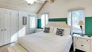 A bedroom with a large bed, a bench, a ceiling fan, and a window with blinds. - Lazy Days by Taylor Made Deep Creek (McHenry)
