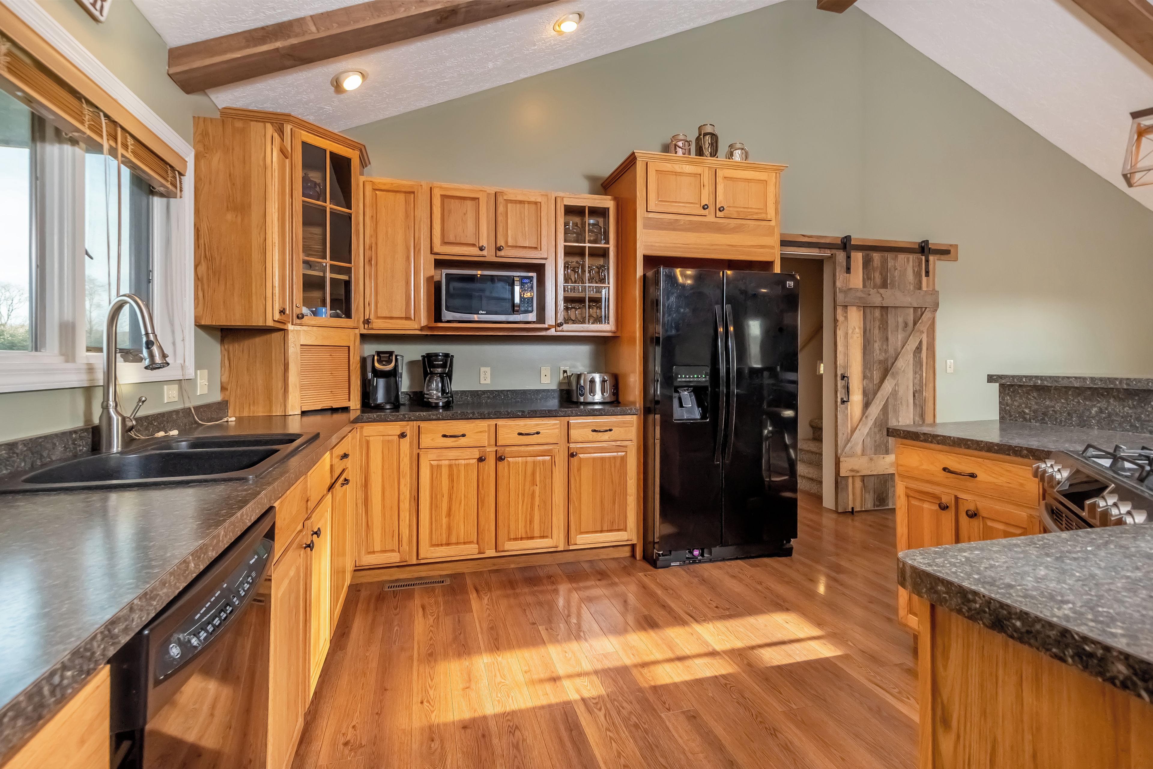 A kitchen with wooden cabinets, a black refrigerator, a microwave, and a dishwasher.