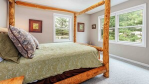 A room with a four-poster bed, large windows, and framed pictures on the walls.