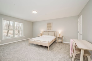 A bedroom with a bed, bedside tables, a desk, and a chair.