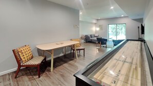Una habitación con mesa de juego de discos, una mesa de comedor con sillas y un sofá.