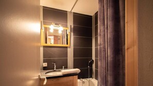 Une salle de bain avec un meuble-lavabo en bois, un miroir, un lavabo et une baignoire.