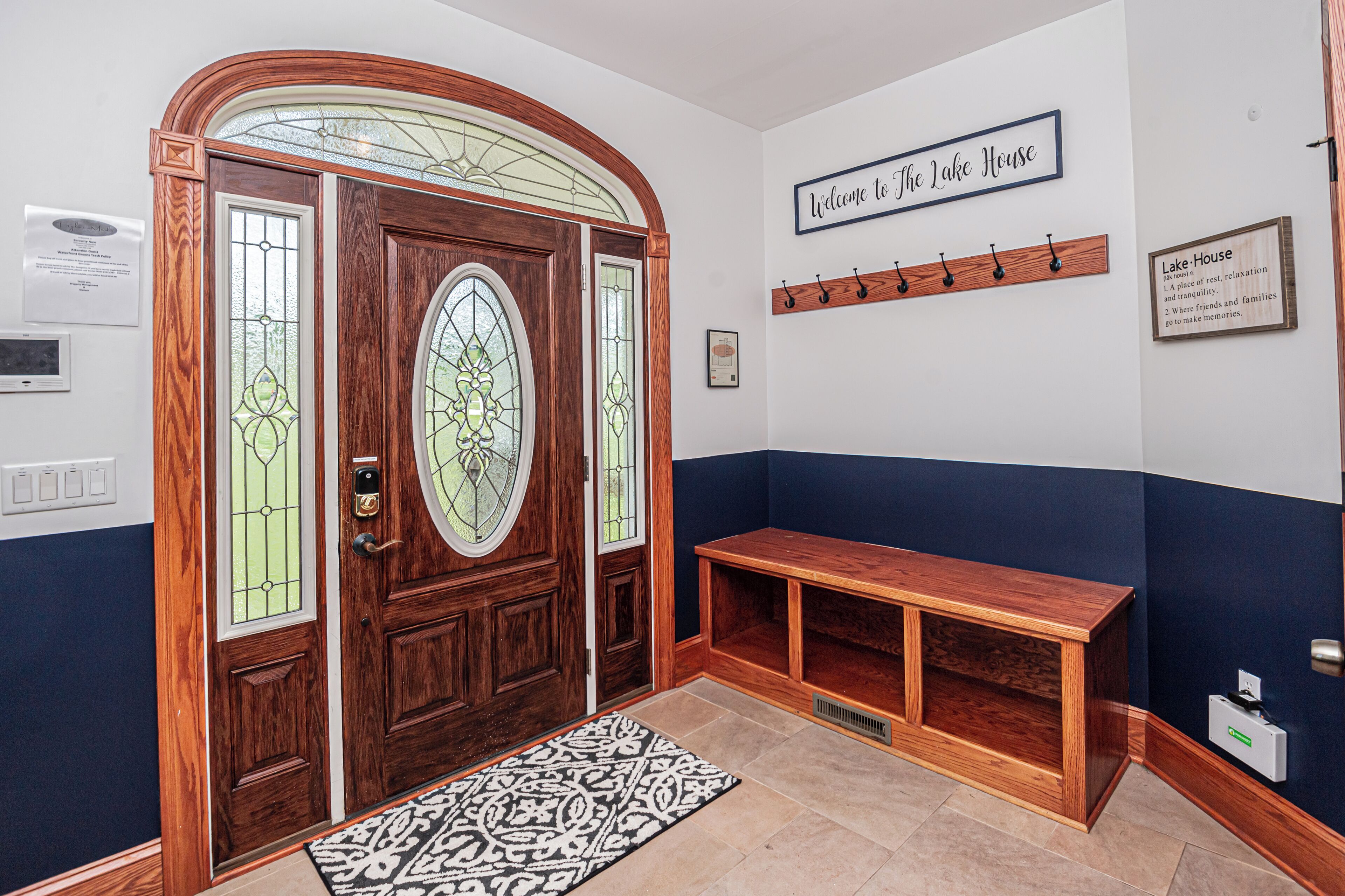 A wooden door with stained glass, a bench, a welcome sign, and a plaque.