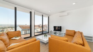 Una sala de estar moderna con un ventanal grande, un televisor de pantalla plana y sofás de cuero.