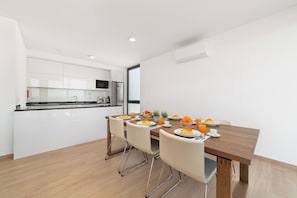 A modern kitchen with white cabinets, a wooden dining table, and a breakfast setting with croissants and orange juice. - Casa do Sol - Holiday Villa with Private Pool By SCH (Salir do Porto)