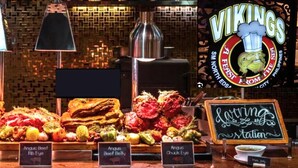 Eine Speisenauslage mit verschiedenen Fleisch- und Gemüsesorten, darunter Rippchen und Rinderbauch, in einem Restaurant.
