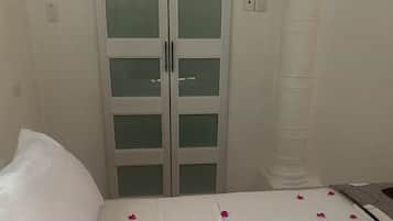 Ein Hotelzimmer mit Bett, weißen Leinen, einem Schrank mit Milchglasüren und einem Handtuch auf dem Bett.