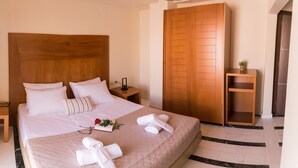 A neatly made bed with white linens, a wooden headboard, and a bedside table with a lamp and a small plant.
