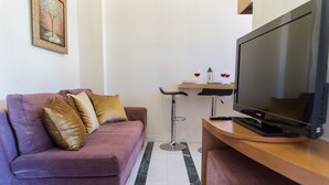 A modern living room with a purple sofa, a flat-screen TV, and a small wooden table.