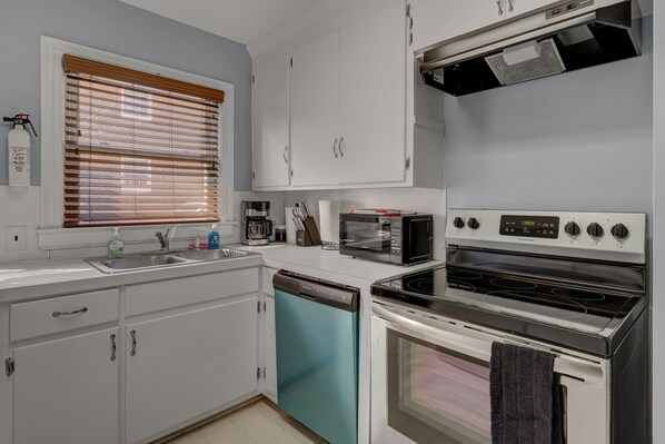 A kitchen with white cabinets, a dishwasher, a microwave, and a stove.