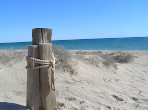 A wooden post with a rope tied around it on a sandy beach with the ocean in the background. - Sandy Feet Retreat (Puerto Penasco, Rocky Point)