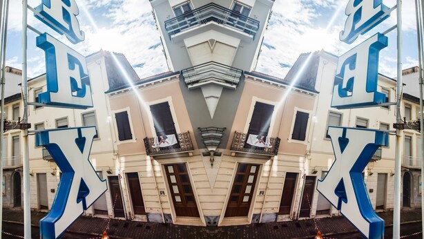 Un edificio con fachada simétrica, varios balcones y una torre central.