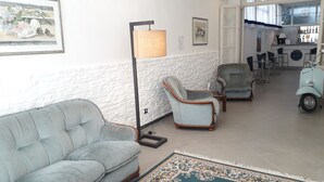 Un salón con un sofá azul claro, dos sillones, una lámpara de pie y una alfombra estampada.